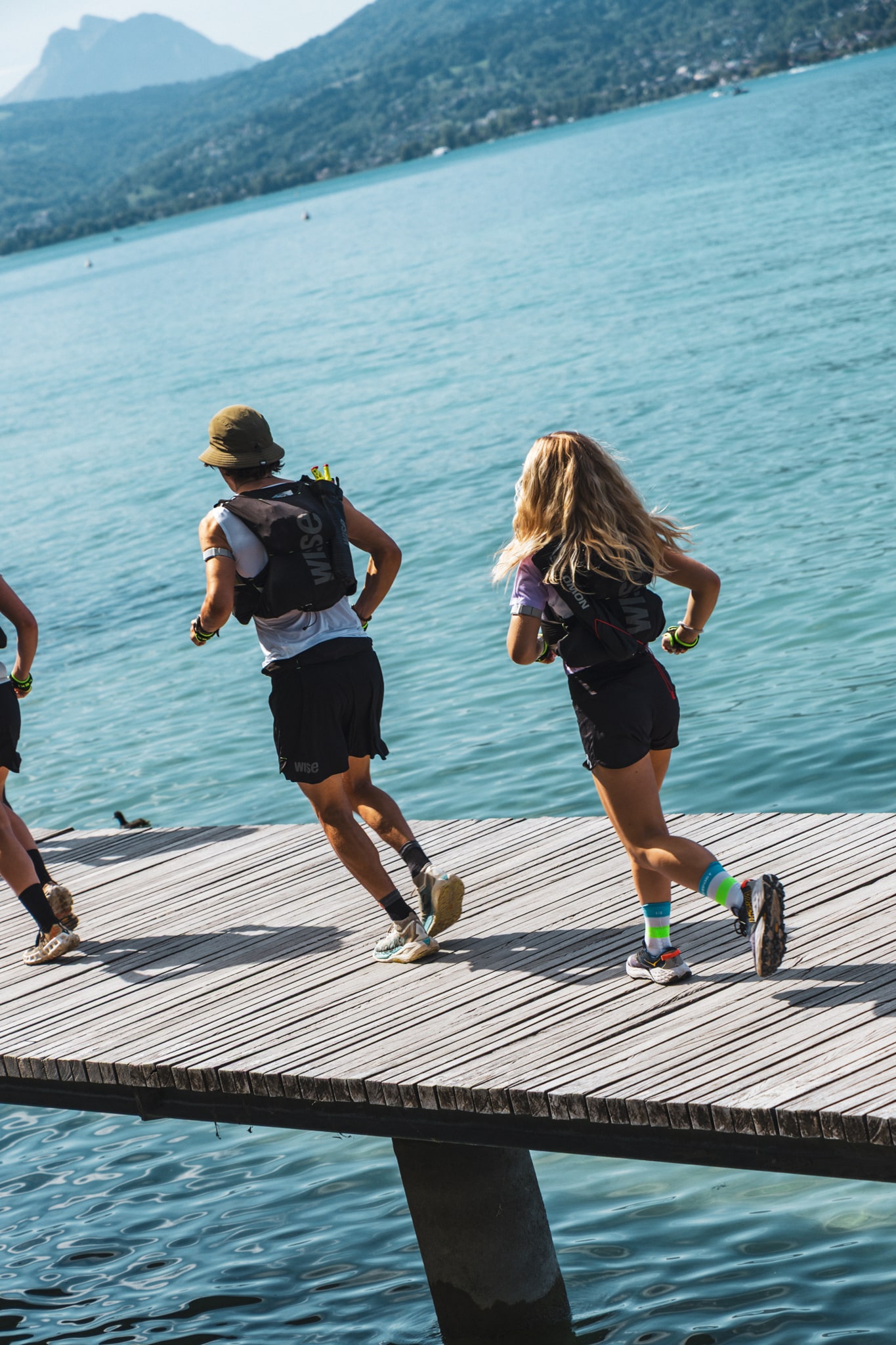 Des participants courent sur un ponton au bord du lac d’Annecy